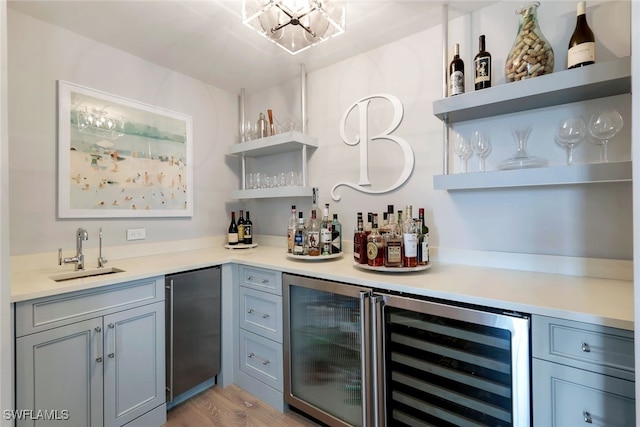 bar with stainless steel refrigerator, light wood-type flooring, sink, and wine cooler