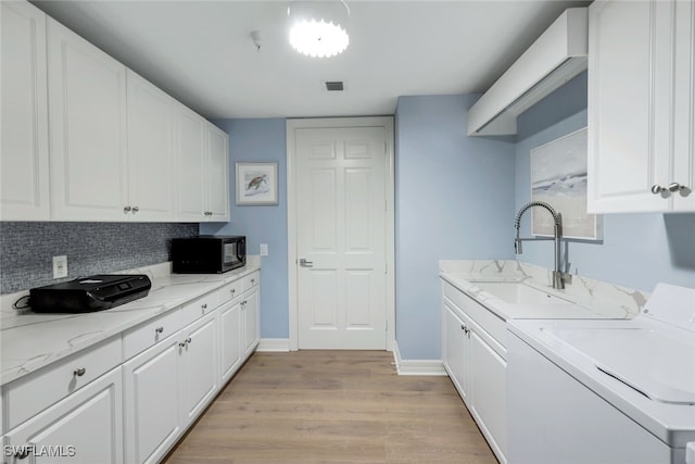 laundry room with washer and dryer, light hardwood / wood-style floors, cabinets, and sink