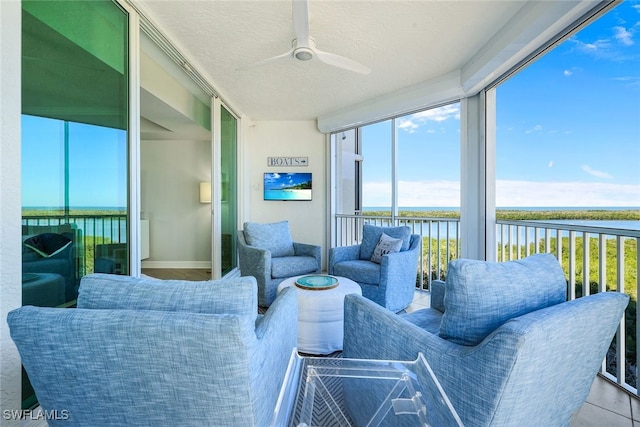 sunroom featuring a water view and ceiling fan