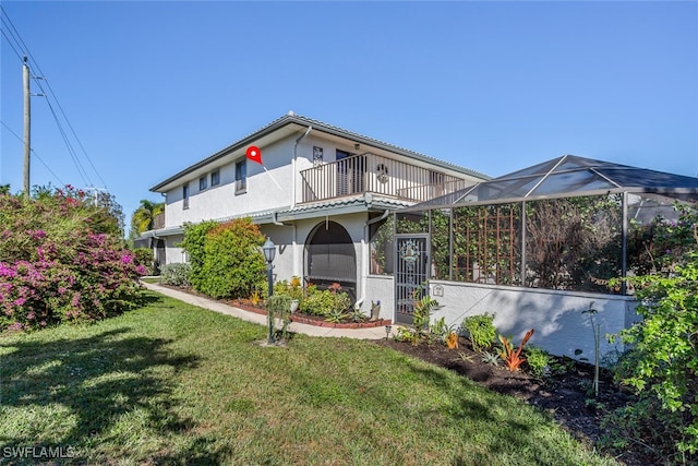 view of front of house featuring a lanai, a balcony, and a front yard