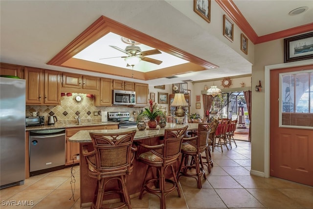 kitchen featuring a center island, a kitchen breakfast bar, ceiling fan, appliances with stainless steel finishes, and decorative light fixtures