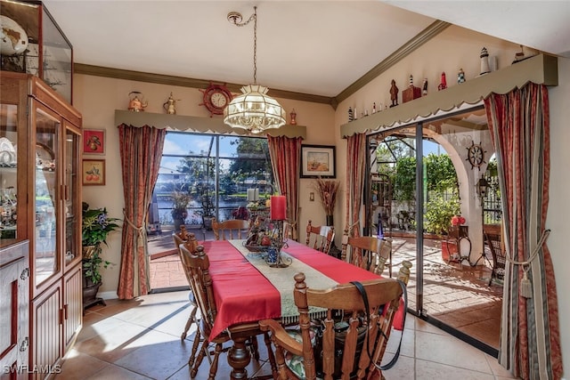 tiled dining space with a notable chandelier, plenty of natural light, lofted ceiling, and ornamental molding