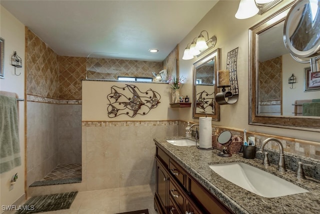 bathroom featuring tile patterned flooring, vanity, a tile shower, and tile walls