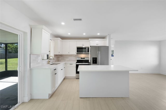 kitchen featuring sink, light hardwood / wood-style flooring, appliances with stainless steel finishes, a kitchen island, and white cabinetry