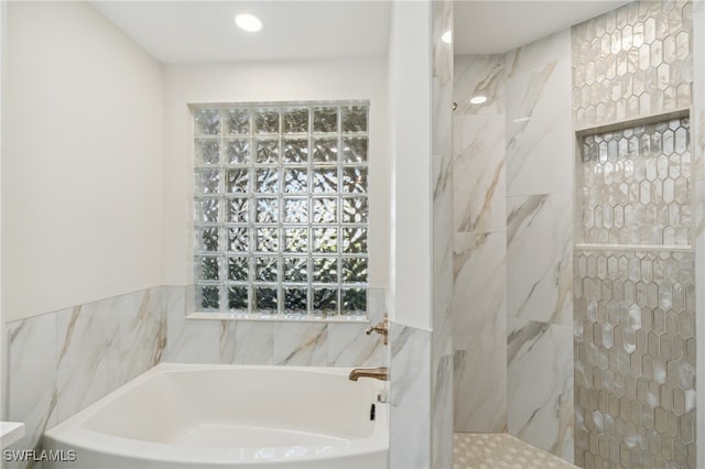 bathroom featuring shower with separate bathtub and tile walls