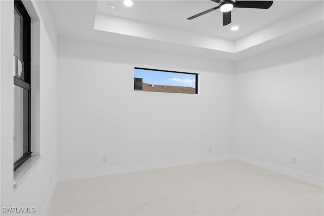 unfurnished room with ceiling fan and a raised ceiling