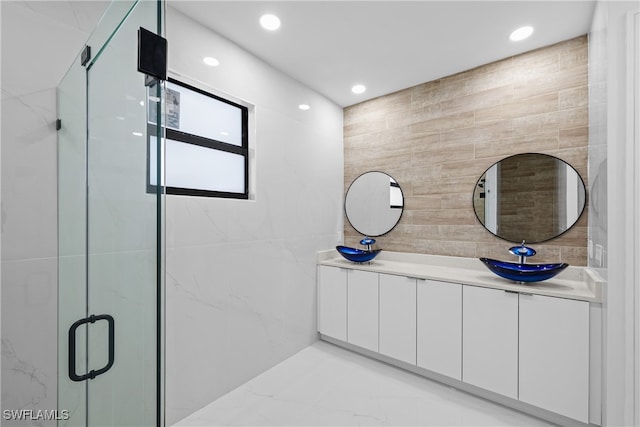 bathroom with vanity, a shower with door, and tile walls