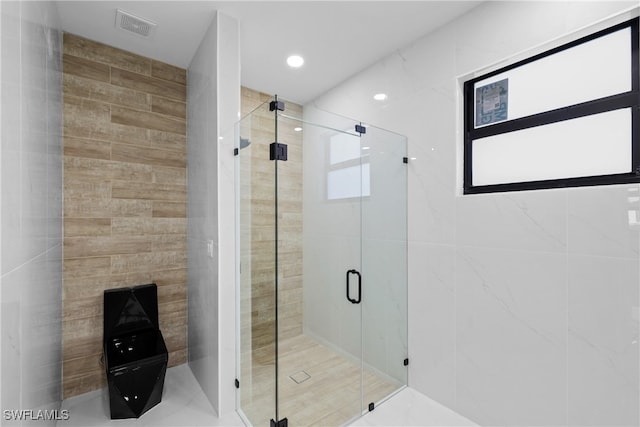 bathroom featuring an enclosed shower and tile walls