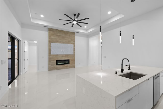 kitchen with decorative light fixtures, white cabinetry, a kitchen island with sink, and light stone counters