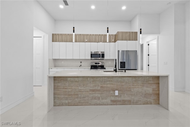 kitchen with stainless steel appliances, sink, decorative light fixtures, a center island with sink, and white cabinets