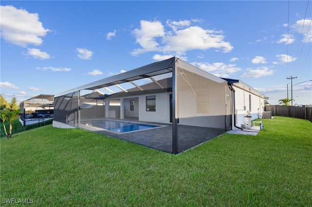 rear view of property with a patio, a fenced in pool, a lanai, and a lawn