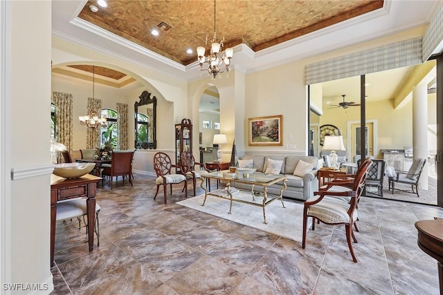 living room with a raised ceiling, crown molding, a towering ceiling, and ceiling fan with notable chandelier