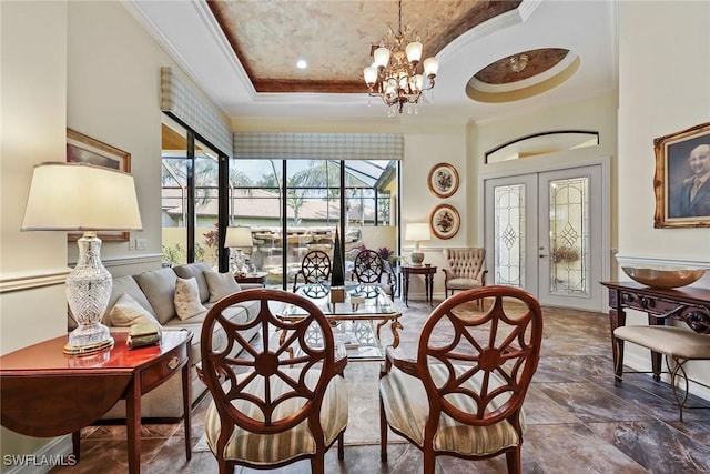 dining space featuring french doors, a high ceiling, a notable chandelier, a tray ceiling, and ornamental molding