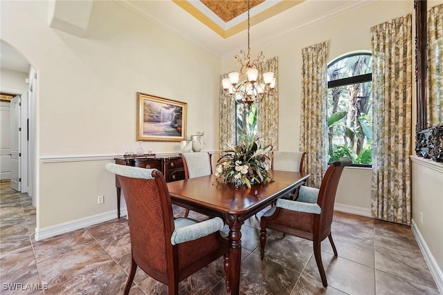 dining space featuring a raised ceiling, crown molding, and a notable chandelier