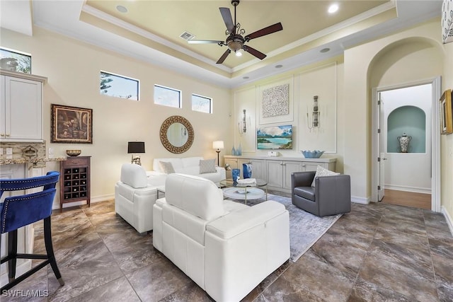 living room featuring a tray ceiling, ceiling fan, and crown molding