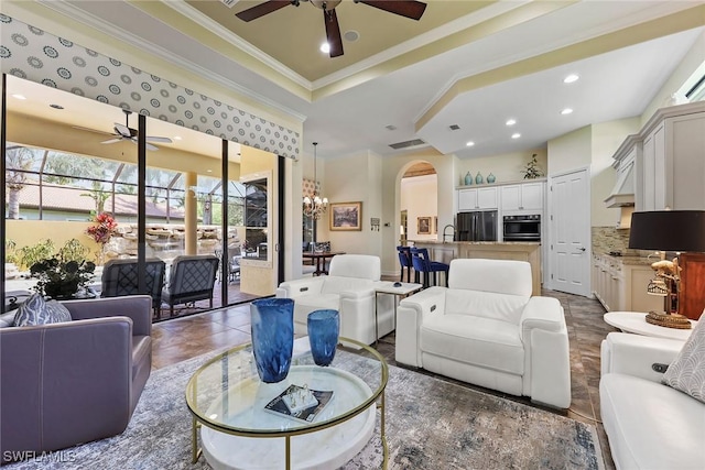 tiled living room with a raised ceiling, crown molding, sink, and an inviting chandelier