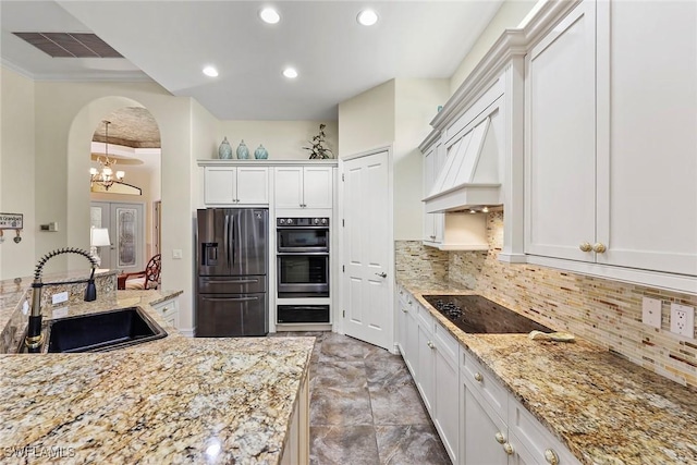 kitchen with decorative backsplash, light stone counters, stainless steel appliances, sink, and white cabinetry