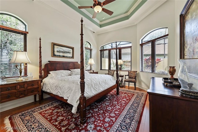 bedroom with hardwood / wood-style floors, ceiling fan, a raised ceiling, and crown molding