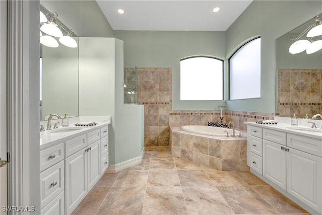 bathroom featuring tiled tub and vanity