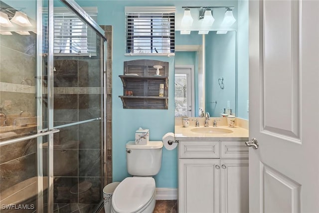 bathroom with vanity, toilet, plenty of natural light, and a shower with shower door