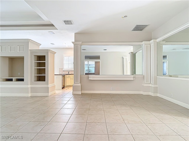 tiled empty room featuring built in shelves and decorative columns