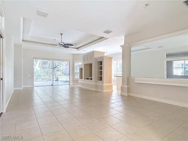 tiled empty room featuring a tray ceiling and ceiling fan