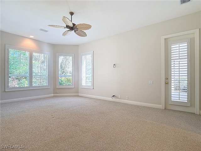 spare room featuring ceiling fan, a healthy amount of sunlight, and light colored carpet