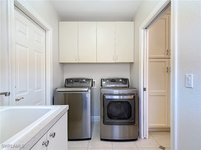 laundry area featuring sink, light tile patterned floors, cabinets, and independent washer and dryer