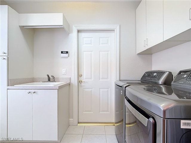 laundry room with washing machine and clothes dryer, sink, light tile patterned floors, and cabinets