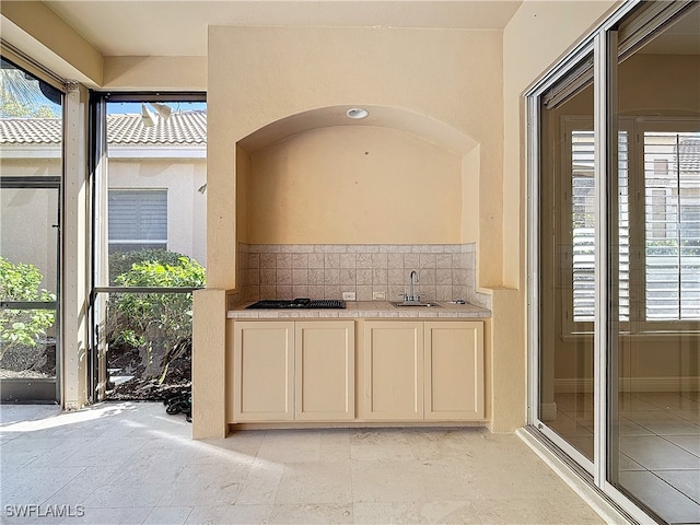 bar featuring backsplash, a wealth of natural light, and sink