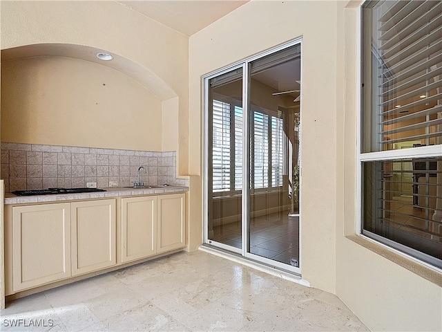 interior space featuring decorative backsplash, black gas cooktop, and sink