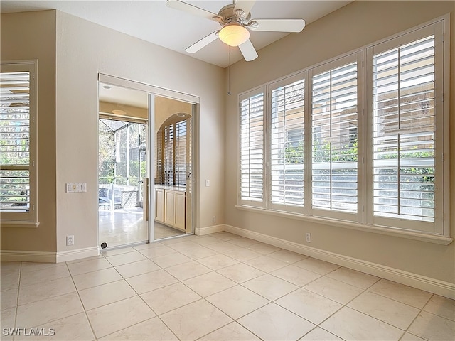 spare room featuring ceiling fan, light tile patterned floors, and a wealth of natural light