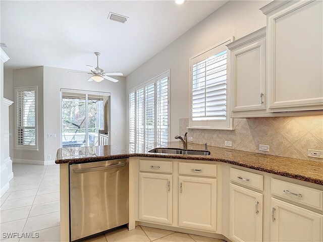 kitchen featuring backsplash, dark stone counters, sink, light tile patterned floors, and dishwasher