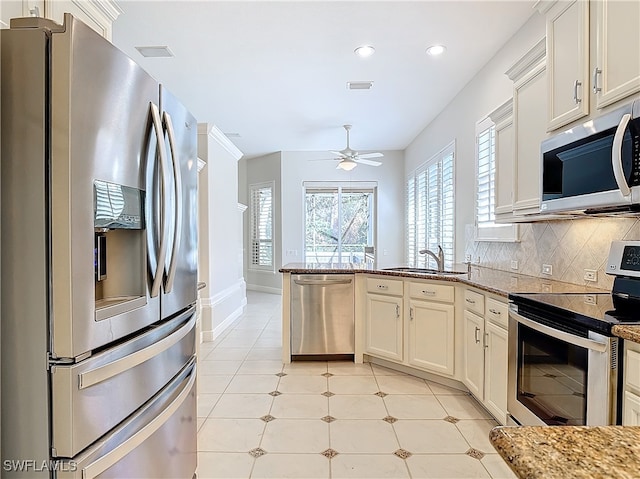 kitchen with backsplash, sink, ceiling fan, appliances with stainless steel finishes, and light stone counters