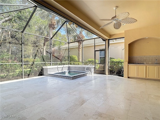 view of patio with ceiling fan, sink, an in ground hot tub, and glass enclosure