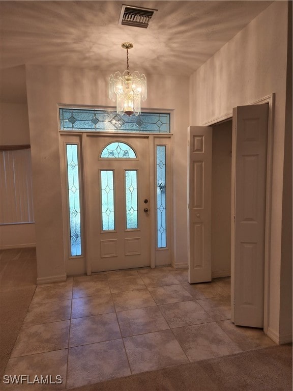 tiled foyer entrance featuring a chandelier