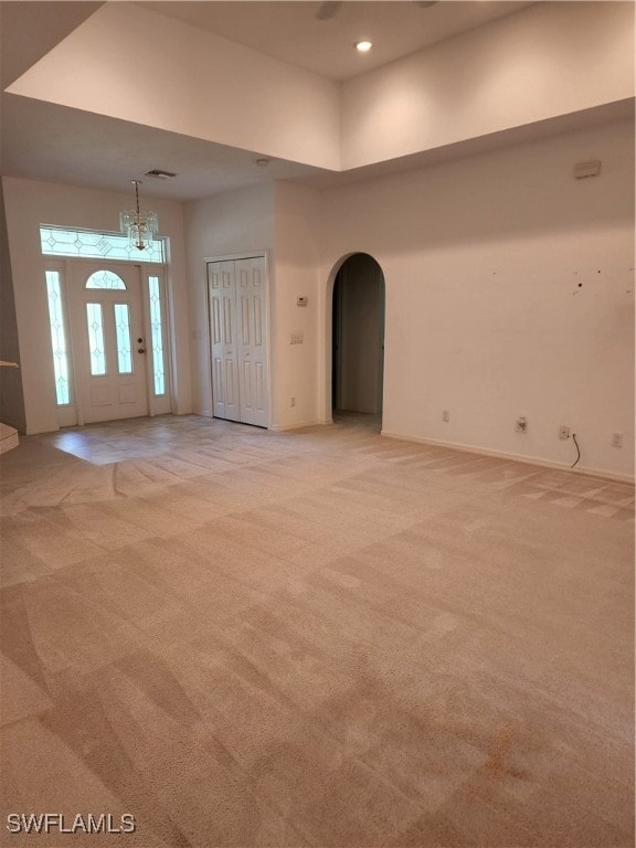 empty room with light colored carpet and a towering ceiling