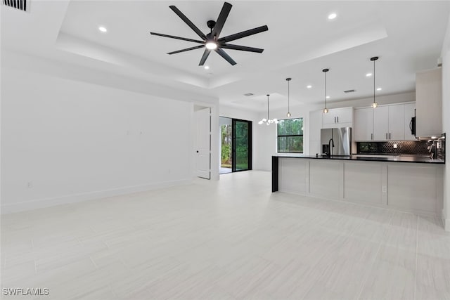 kitchen featuring hanging light fixtures, stainless steel fridge with ice dispenser, a tray ceiling, white cabinets, and ceiling fan with notable chandelier