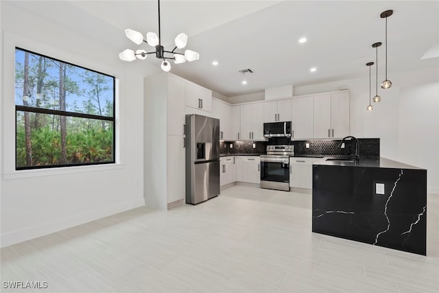 kitchen featuring appliances with stainless steel finishes, tasteful backsplash, sink, decorative light fixtures, and white cabinetry