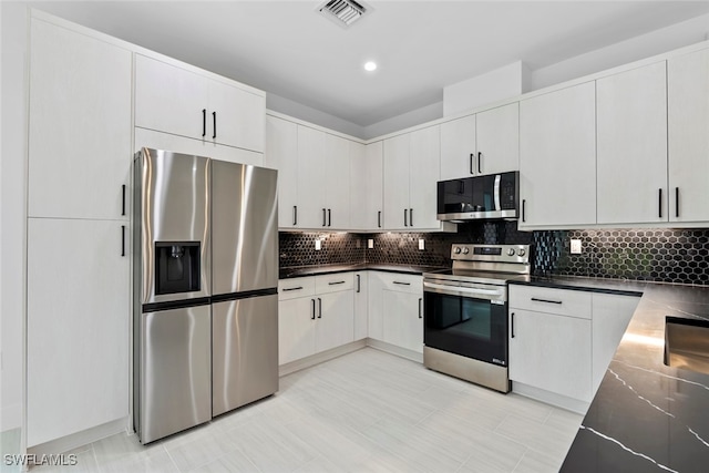 kitchen with white cabinets, decorative backsplash, light tile patterned floors, and stainless steel appliances