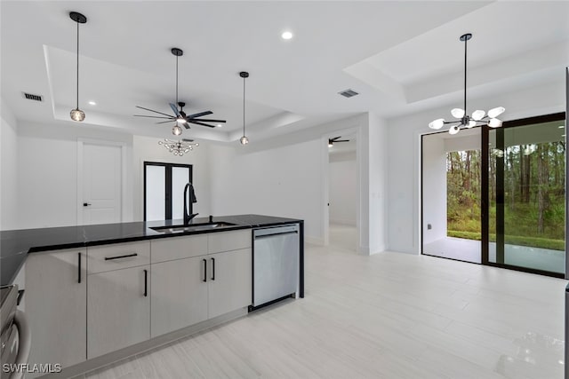 kitchen with dishwasher, sink, hanging light fixtures, a raised ceiling, and ceiling fan with notable chandelier