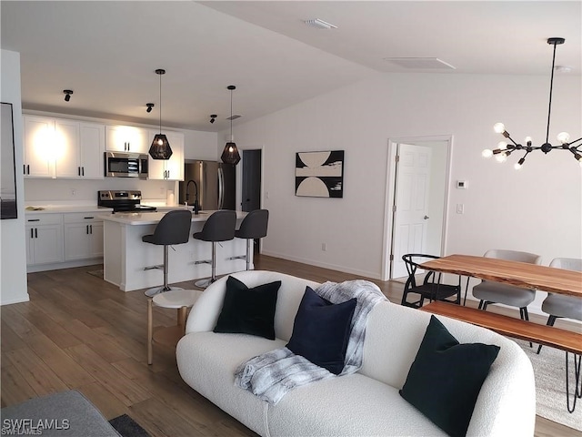 living room with dark hardwood / wood-style flooring, lofted ceiling, and a notable chandelier