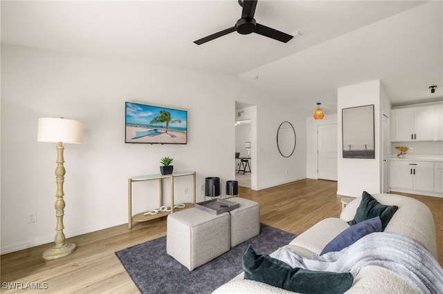 living room featuring lofted ceiling, ceiling fan, light wood-style flooring, and baseboards