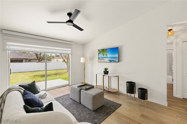 living area with vaulted ceiling, wood finished floors, a ceiling fan, and baseboards