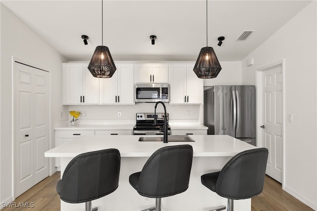 kitchen with stainless steel appliances, light countertops, visible vents, and decorative light fixtures