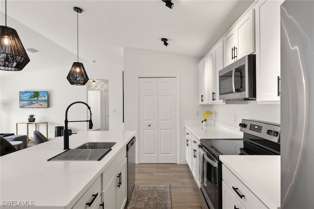 kitchen with white cabinets, light wood-style floors, light countertops, appliances with stainless steel finishes, and hanging light fixtures