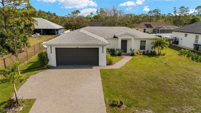 ranch-style home featuring decorative driveway, roof with shingles, fence, a garage, and a front lawn