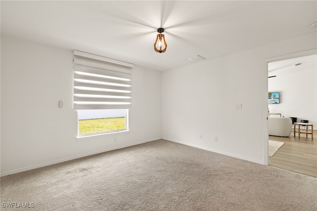 carpeted spare room featuring visible vents and baseboards