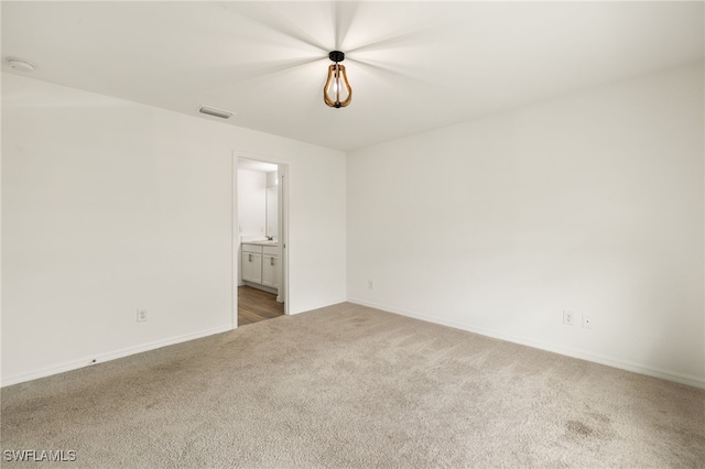 unfurnished bedroom with carpet floors, visible vents, and ensuite bath