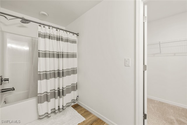 bathroom featuring shower / bath combination with curtain, baseboards, and wood finished floors